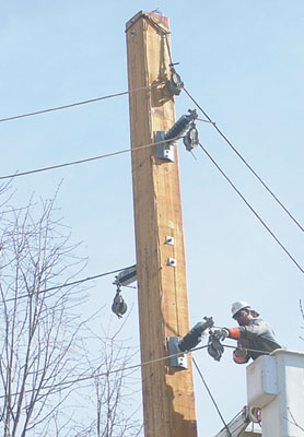 A city-contracted worker teeters high up on a new high-voltage transmission power line last year. City council is considering increasing electric rates for residents, while lowering the rates for larger users.<br>dailystandard.com