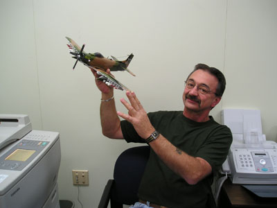 Tom Risch of Celina displays the Skyraider model from his collection of 35 of the mahogany model airplanes, which line the walls of his office at Mercer County Veterans Service in Celina.<br>dailystandard.com