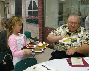   Eight-year-old Morgan Beatty shows diner Don Hare of Celina the large variety of tempting desserts prepared by Giving Thanks workers. Beatty was one of several dozen servers on hand at Celina High School.<br>dailystandard.com