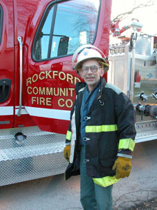 Ralph Rhoades poses in full firefighter gear at the scene of a recent non-injury house fire in the Rockford area. The 78-year-old Rockford fire chief has been a volunteer firefighter for more than 61 years and has served as fire chief for nearly four decades.<br>dailystandard.com