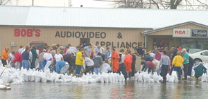 Volunteers fill sandbags near Bob's Audiovideo in Celina this morning and then stacked them around Community Medical Center. The Beaver Creek was out of its banks this morning, with water up to U.S. 127 and threatening several businesses. As of press time, water had not yet entered the medical center or Breakway RecPlex.<br>dailystandard.com