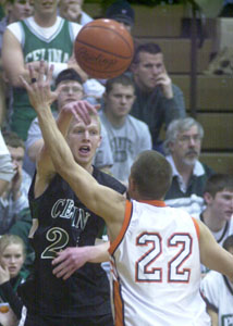 Celina's Eric Klosterman, left, passes the ball over Coldwater's Craig Wellman, 22, during their game on Saturday night. Klosterman scored six points in the Bulldogs' 52-39 win.<br>dailystandard.com