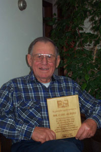 St. Henry resident Carl Albers displays the plaque he received last month recognizing his dedication toward the development of a farrow-to-finish hog operation to benefit St. John Bosco Boys' Home in Jamaica. <br>dailystandard.com