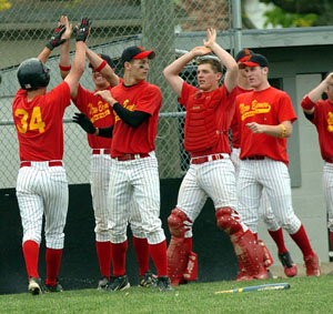 New Bremen players celebrate after scoring a run during Monday's Division IV district semifinal contest against Marion Local at Minster's Hanover Street Park. New Bremen got a big day from Alex Leugers on the mound and at the plate leading the Cardinals to a 5-1 win over Marion Local.<br>dailystandard.com
