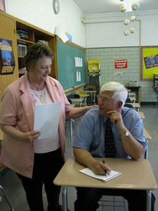 Teacher Ronda Shelby, standing, gives her former student and current assistant high school principal, Dennis Vossler, a watchful eye at St. Marys Memorial High School. The pair are retiring from the school after a combined 75 years of service.<br>dailystandard.com