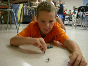Kruse Ranly of Fort Recovery spins jacks on the floor after he and other students learned about different games played by children in the 1600-1700s during this summer's Kid Connections program.<br>dailystandard.com