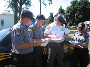Auglaize County Sheriff's Deputy Doug Burke checks schedules for members of Auglaize County Explorer Post 600 as Lt. Brian Vernon, at left, First Sgt. Sam Blank and Second Sgt. Leigh McCullough look on. They are among 11 Explorers on duty this week at the Auglaize County Fair.<br>dailystandard.com