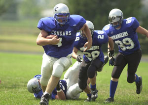 Mercer County's Chris Guggenbiller, 4, breaks away from a pair of West Ohio defenders during first half action on Saturday. Guggenbiller scored twice and rushed for 56 yards in the Cougars' 41-0 win.<br>dailystandard.com