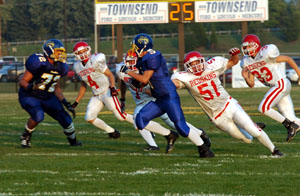 St. Henry's Kyle Bruggeman, 20, tries to run behind the block of teammate Cory Borgerding, 68, during the Redskins' game against Lehman on Saturday. Bruggeman had 186 yards and three touchdowns to help St. Henry open the 2005 season with a 34-21 win over Lehman.<br>dailystandard.com