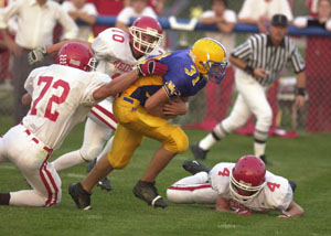 Marion Local's Curtis Moeller, 31, breaks through the arms of St. Henry's Ryan Lefeld, 72, during Friday's game at Booster Field. Moeller had 68 yars and a touchdown in the Flyers 17-16 victory over the Redskins.<br>dailystandard.com