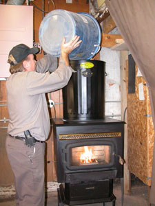 Dave Wenning pours a mix of shelled corn and wood pellets into his American Harvest multi-fuel stove. Wenning uses the unconventional heating source to warm the building that houses his business, C Creations Auto Trim & Upholstery in Celina.<br></br>dailystandard.com
