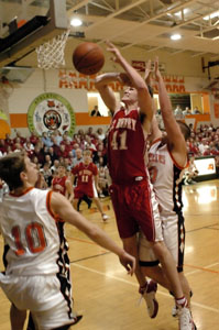 St. Hentry's Kurt Huelsman, 41, gets fouled from behind by Versailles' Zac Richard, right, as Tigers teammate Jeremy shardo, 10, looks on during their Midwest Athletic Conference contest on Friday night. Huelsman scored 23 points and had 10 rebounds to help push St. Henry past Versailles on the road, 61-48.<br></br>dailystandard.com