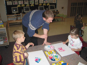 Aaron Winner, a gifted education teacher at Parkway Local Schools, facilitates a painting session with Fort Recovery students Kristen Keller and Aaron Homan. Wright State University students and young teachers read to students Tuesday night, while parents listened to a lecture about development of a child's brain.<br></br>dailystandard.com