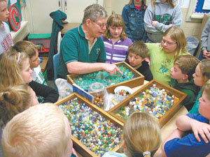 Phil Fennig of Celina shows off a portion of his marble collection to a group of fourth-graders at Celina East Elementary on Thursday. Fennig, a school maintenance worker, shares his beloved hobby with the students each year.<br></br>dailystandard.com