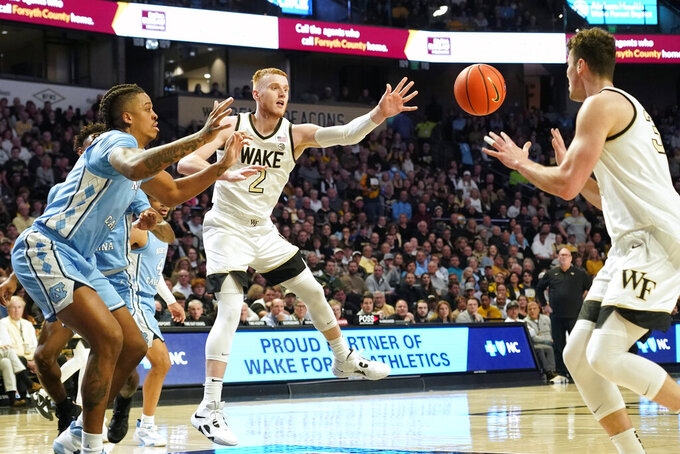 Wake Forest guard Cameron Hildreth, center, passes the ball toward Wake Forest forward Matthew Marsh, right, as North Carolina forward Armando Bacot, left, defends during the first half of an NCAA college basketball game in Winston-Salem, N.C., Tuesday, Feb. 7, 2023. (AP Photo/Chuck Burton)