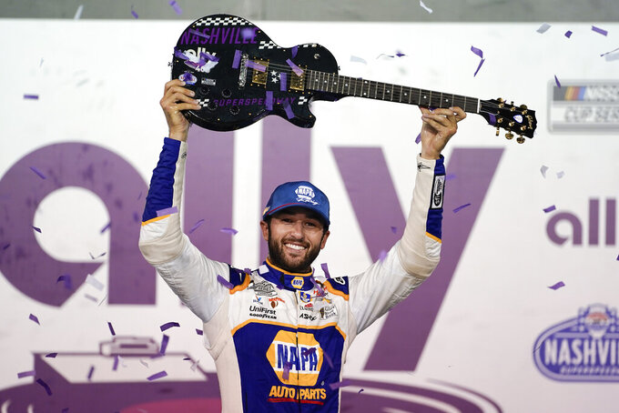 Chase Elliott holds the guitar presented to him after winning a NASCAR Cup Series auto race Sunday, June 26, 2022, in Lebanon, Tenn. (AP Photo/Mark Humphrey)