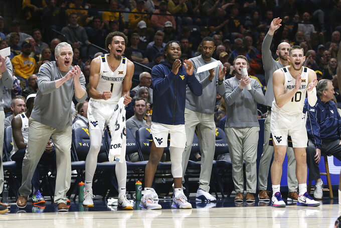 West Virginia players and coaching staff react from the bench during the first half of the team's NCAA college basketball game against Iowa State on Wednesday, Feb. 8, 2023, in Morgantown, W.Va. (AP Photo/Kathleen Batten)