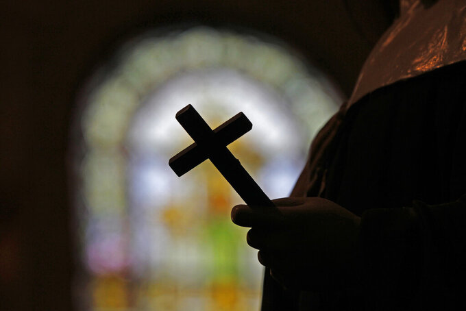 FILE - This Dec. 1, 2012 file photo shows a silhouette of a crucifix and a stained glass window inside a Catholic Church in New Orleans. The FBI has opened a widening investigation into sex abuse in the Roman Catholic Church in New Orleans going back decades, a rare federal foray into such cases looking specifically at whether priests took children across state lines to molest them, officials and others familiar with the inquiry told The Associated Press.     (AP Photo/Gerald Herbert, File)