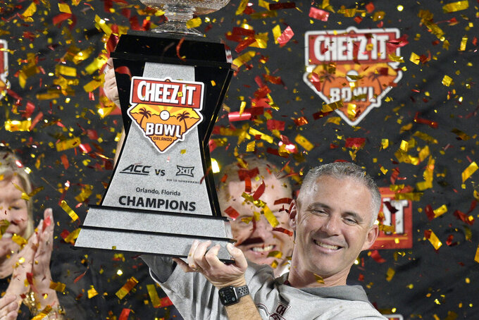 FILE - Florida State head coach Mike Norvell lifts the trophy after the team's win against Oklahoma in the Cheez-It Bowl NCAA college football game, on Dec. 29, 2022, in Orlando, Fla. Norvell, whose team ended last season with a six-game winning streak, was rewarded with a three-year contract extension that will pay him an average of $8.05 million annually through 2029, rhe school announced Wednesday, Feb. 8, 2023.
 (AP Photo/Phelan M. Ebenhack, File)