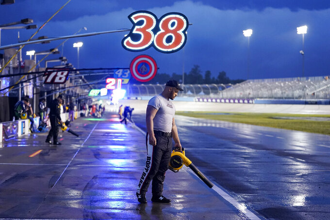 Jourdan Osinskie, the jack man on the pit crew for driver Todd Gilliland, tries to dry off their pit box during a storm delay at a NASCAR Cup Series auto race Sunday, June 26, 2022, in Lebanon, Tenn. (AP Photo/Mark Humphrey)