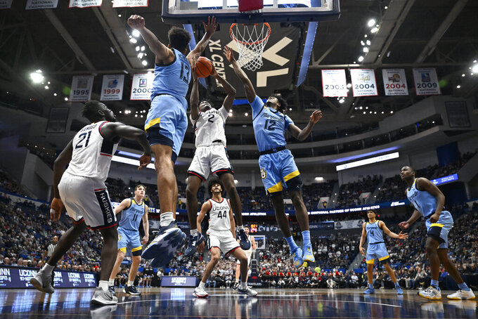 UConn's Tristen Newton (2) goes up for a basket between Marquette's Oso Ighodaro (13) and Marquette's Olivier-Maxence Prosper (12) in the second half of an NCAA college basketball game, Tuesday, Feb. 7, 2023, in Hartford, Conn. (AP Photo/Jessica Hill)