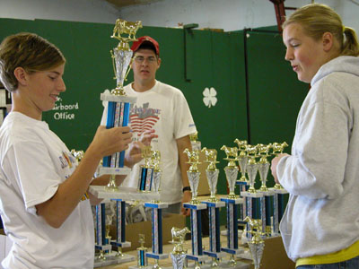 Mercer County Junior Fair board member Karen Hein, 15, of Maria Stein, takes a close look at one of the dairy trophies to be awarded at this year's Mercer County Fair, as other members, Jordan Hellwarth, 18, of Celina, and Sara Broering, 17, also of Maria Stein, look on.<br>dailystandard.com