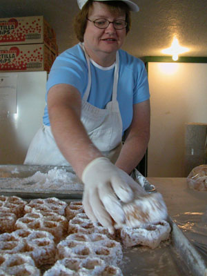   Dianna Ireton places another delicious waffle on the tray after rolling it in powdered sugar early this morning in the Knights of Columbus building at the Mercer County Fair. Center photo, other K of C volunteers, Dick Colson (at right) and Carl Deitsch, fry up the sweet creations three at a time.<br>  <br>dailystandard.com