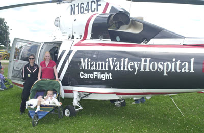Christi Zwiebel of Coldwater and her sons, infant Lucas and 2 year-old Zachary, stand beside the CareFlight helicopter from Miami Valley Hospital in Dayton during the Public Safety Show Saturday afternoon at the Mercer County Banner Fair. Looking on at left is flight nurse Linda Greenberg, part of the three-member crew. The Zwiebels all have needed the services of CareFlight since March.<br>dailystandard.com