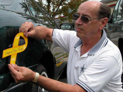 Jim Fischer, of Celina, places a magnetic yellow Support Our Troops ribbon on his car. Fischer, who has served in the U.S. Navy, has a step-son, U.S. Navy Lt. Lonnie Applegate, who has just returned home from serving in Iraq, and a son-in-law, Tom Harrington, with the Army National Guard, who will be leaving for Iraq in September.<br>dailystandard.com