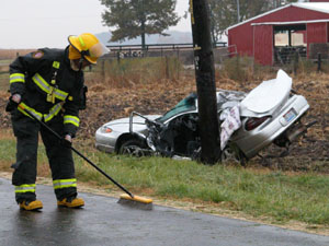 A New Bremen firefighter sweeps debris from an accident along County Road 66A that claimed the life of two Marion Local High School students Wednesday. David Gerlach, 16, and Corey Albers, 17, were killed when the car Gerlach was driving struck a utility pole after veering off the wet pavement at 10:24 a.m.<br>dailystandard.com