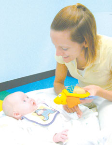 Three-month-old infant Summer Wilson smiles as nursery caregiver Carol Steinbrunner plays with her at Stepping Ahead Learning Center in Coldwater. The childcare center is one of six local facilities and two area homecare providers that qualified to participate in First Steps, a state-funded program for infants and toddlers.<br>dailystandard.com