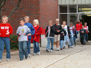 A stream of New Bremen elementary students carry an extra-long red ribbon in their hands as they set out to surround their building Wednesday afternoon. The 600 or so children were participating in the activity in observance of national Red Ribbon Week, an event to promote alcohol- and drug-free schools. After 