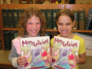 Rarrrrrrrrrrrrr-- Samantha Fortman, left, and Nicole Trydle, both St. Marys Holy Rosary School students, make monster faces at the St. Marys library after listening to a presentation by author Erik Jon Slangerup, who wrote 