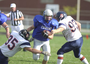 Mercer County Cougars running back Chad Timmerman busts through a pair of Kosciusko County defenders during a run on Saturday afternoon. The Mercer County Cougars clinched home field advantage for the playoffs following the 34-20 win.<br></br>dailystandard.com