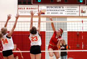 St. Henry's Betsy Hoying, 11, spikes over the outstretched arms of Versailles defenders, Mallorie Brand, 34, and Laura Grilliot. Hoying had 21 kills in the Redskins' four-game win over the Tigers.<br></br>dailystandard.com