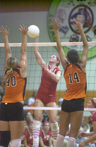 St. Henry's Kayla Lefeld, middle, spikes the ball between Coldwater's Brittany Klenke, 40, and Lindsey Bruns, 14, during the Midwest Athletic Conference match on Thursday night. St. Henry defeated Coldwater in four games to stay unbeaten in the MAC.<br></br>dailystandard.com