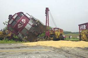 An R.J. Corman train rests on its side after it was struck Wednesday morning by a grain truck carrying shelled corn along state Route 219 south of St. Marys. Three people, including two men on the train, received minor injuries in the crash. See related photo on back page.<br></br>dailystandard.com