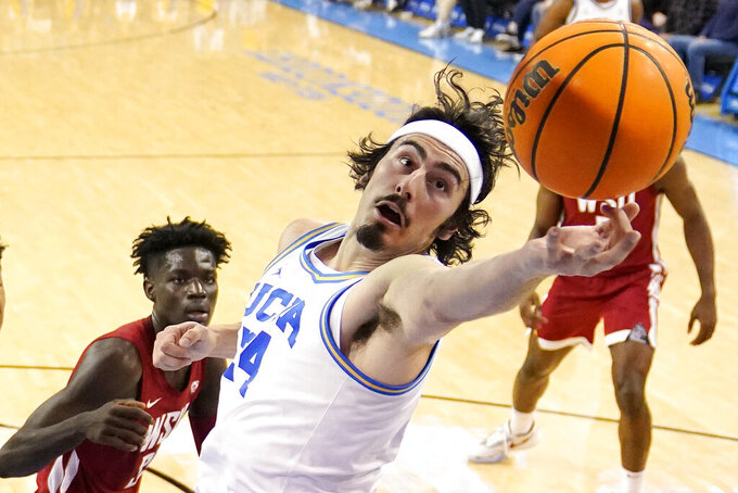 UCLA guard Jaime Jaquez Jr., right, reaches for a rebound as Washington State forward Mouhamed Gueye watches during the first half of an NCAA college basketball game Saturday, Feb. 4, 2023, in Los Angeles. (AP Photo/Mark J. Terrill)