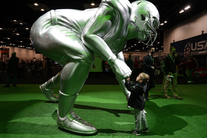 A child fist bumps a statue in Indianapolis, Saturday, Jan. 8, 2022. Alabama plays Georgia in the NCAA college football championship game on Monday. (AP Photo/Paul Sancya)